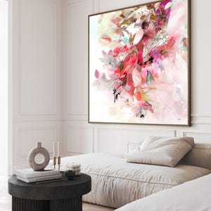 Large framed abstract art print featuring a vibrant floral design in shades of pink, red, and white. The artwork has a watercolor effect with delicate lines and a soft, dreamy aesthetic. The frame is a warm brown color.