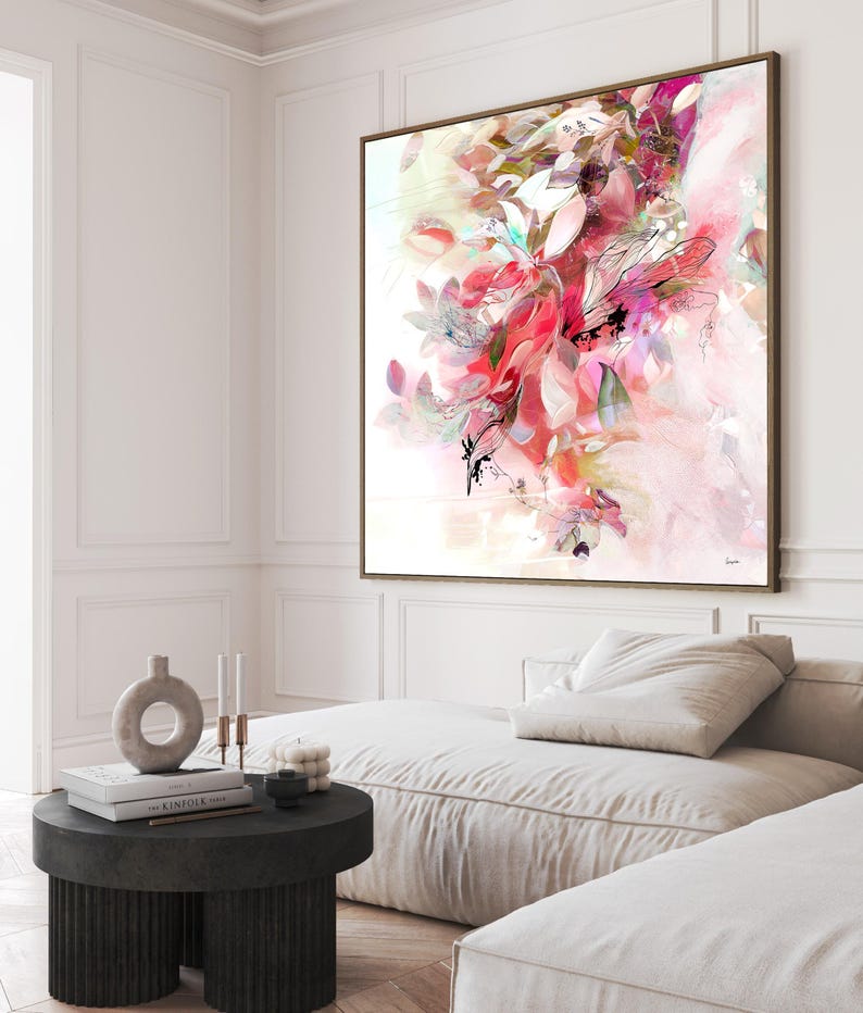 Large framed abstract art print featuring a vibrant floral design in shades of pink, red, and white. The artwork has a watercolor effect with delicate lines and a soft, dreamy aesthetic. The frame is a warm brown color.