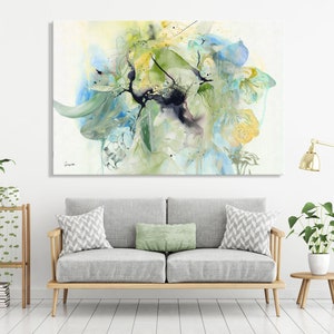 Abstract watercolor painting featuring a large, colorful floral design in shades of blue, green, and yellow. The painting has a soft, ethereal feel and is perfect for adding a touch of nature to any room.