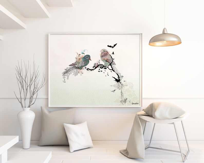 A framed print of two birds perched on a branch with a floral design. The birds are a light blue and a pink color. The background is a light green with a subtle pattern.