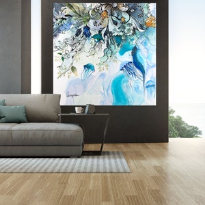 Abstract watercolor painting featuring blue jellyfish and floral elements in shades of blue, green, and white. The painting is framed and hanging on a wall in a modern living room.