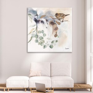Watercolor painting of a bird perched on a branch with eucalyptus leaves. The artwork features soft, muted tones of beige, gray, and green. The bird is light brown, and the leaves are various shades of green. The background is a soft, abstract wash of colors. The painting has a calming and serene atmosphere, perfect for a living room or bedroom. The style is modern and minimalist, with a focus on natural elements.