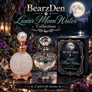 May include: Two decorative glass bottles from the BearzDen Lunar Moon Water Collection. One bottle is spherical with a rose gold base and iridescent texture, the other is heart-shaped with dark metal, green gems, and a faceted crystal stopper.