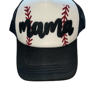 May include: Black and white baseball cap with the word "mama" in black script across the front. The white front panel has red stitching details, resembling a baseball. The cap has a black mesh back and a black brim.