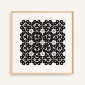 Peut inclure: Œuvre d'art encadrée avec un motif géométrique noir et blanc. Le design est composé de formes florales et étoilées répétitives, créant un motif symétrique et complexe. L'œuvre est présentée dans un cadre en bois de couleur claire.