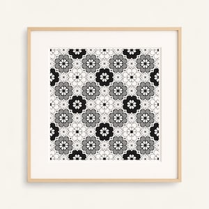 Peut inclure: Une impression encadrée présentant un motif floral répétitif en noir et blanc. Le motif comprend des fleurs stylisées et des formes géométriques, créant une œuvre d'art symétrique et décorative. L'impression est encadrée dans un cadre en bois clair.