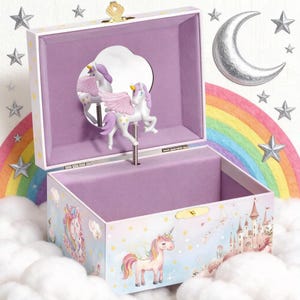 May include: A light pink musical jewelry box with a unicorn theme. The box features a unicorn figurine with pink wings and a mirror inside. The exterior is decorated with unicorns, castles, and rainbows. The box is open, revealing a purple interior.