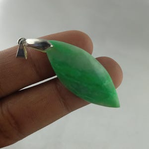 Può includere: Un ciondolo in giada verde a forma di foglia con una cauzione color argento. La giada lucida ha un aspetto marmorizzato con varie sfumature di verde. Gioielli da indossare.