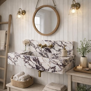 Puede incluir: Un lavabo rectangular montado en la pared hecho de m&aacute;rmol blanco con vetas de color p&uacute;rpura oscuro. El lavabo cuenta con grifer&iacute;a de lat&oacute;n, un espejo redondo con marco de madera encima y un toallero de escalera de madera a la izquierda.