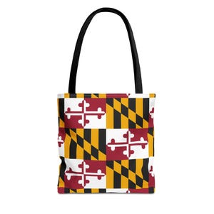 Może przedstawiać: Torba typu tote z wzorem flagi stanu Maryland. Torba ma czarny uchwyt i powtarzający się wzór czerwonych, białych, czarnych i złotych elementów flagi Maryland. Torba jest wykonana z wytrzymałej tkaniny.