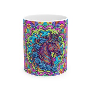 May include: White ceramic mug featuring a colorful unicorn design. The unicorn is adorned with blue roses and set against a vibrant, psychedelic mandala background. The mug is suitable for hot or cold beverages.