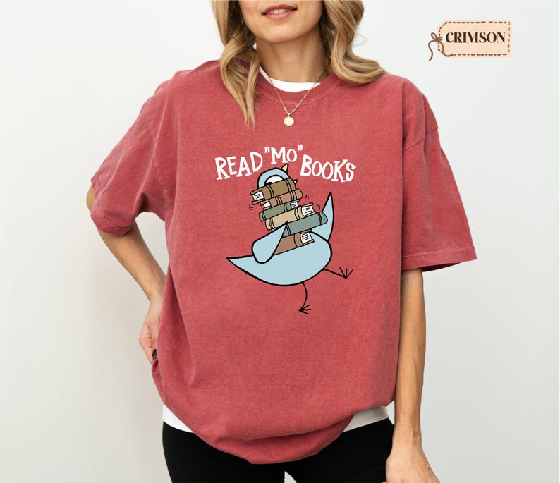 A woman wearing a red t-shirt with a graphic design of a bird carrying books.
