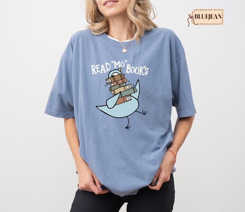 A woman wearing a blue t-shirt with a graphic design of a bird carrying a stack of books.