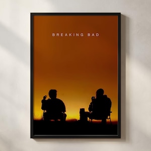 May include: Framed art print with a sunset scene and two seated silhouettes. The text "BREAKING BAD" is in white at the top. The print is in a black frame, suitable for wall display. The overall theme is a TV show.