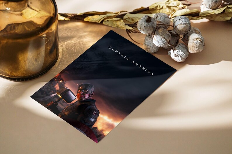 May include: A Captain America print featuring the superhero in a battle scene. The print has the words "CAPTAIN AMERICA" in white text. The image is on a dark background with a fiery glow. A decorative glass bottle and dried floral arrangement are also in the image.