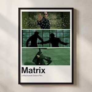 May include: A framed poster for "The Matrix" film, featuring three action scenes. The poster has a white base with the film's title in bold white letters. The text "a Wachowski Sisters Film" is below the title. The poster is in a black frame.