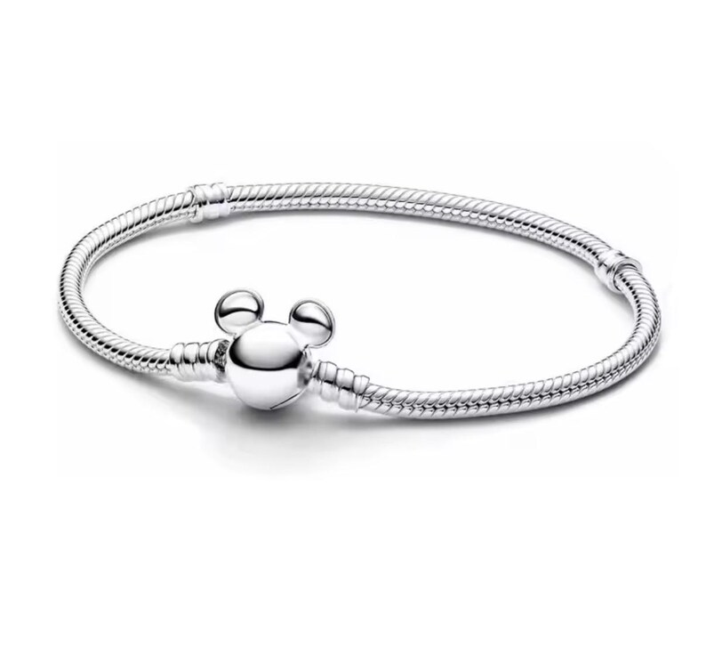 Puede incluir: Una pulsera plateada con un charm de Mickey Mouse. La pulsera tiene un dise&ntilde;o de cadena de serpiente y un cierre redondo. El charm es una representaci&oacute;n estilizada de la cabeza de Mickey Mouse. Longitud: aprox. 18 cm.