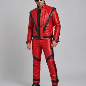 May include: A red leather jacket and matching red leather pants featuring black leather accents, V-shaped paneling, a high collar, and black buckled straps at the cuffs and ankles. The jacket includes a front zipper closure and quilted shoulder details.