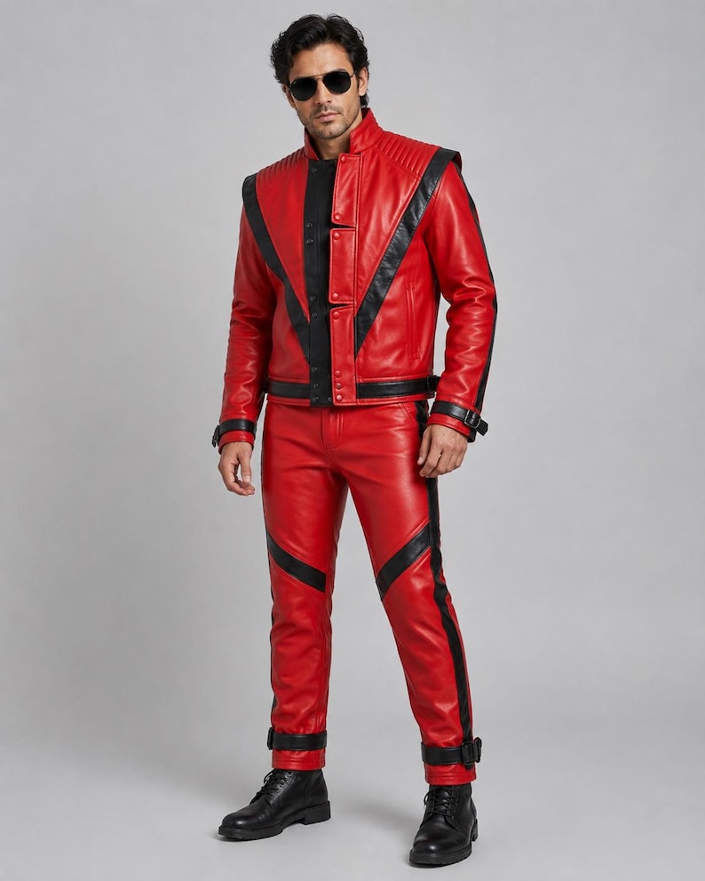 May include: A red leather jacket and matching red leather pants featuring black leather accents, V-shaped paneling, a high collar, and black buckled straps at the cuffs and ankles. The jacket includes a front zipper closure and quilted shoulder details.