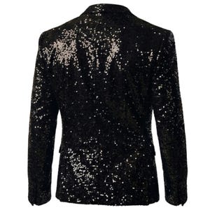 Pode incluir: Um blazer preto coberto de lantejoulas. O casaco tem um fecho cl&aacute;ssico de dois bot&otilde;es e lapelas entalhadas. As lantejoulas d&atilde;o ao blazer um aspeto brilhante e texturizado. As mangas s&atilde;o compridas e o blazer tem um corte sob medida.