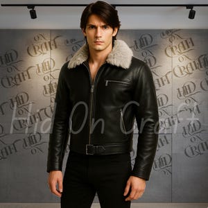 Puede incluir: Chaqueta de cuero negra con cuello de piel clara. La chaqueta tiene cierre de cremallera, un pequeño bolsillo en el pecho y un cinturón en la cintura. El modelo lleva pantalones negros.