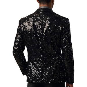 Pode incluir: Um blazer preto com lantejoulas e lapela cl&aacute;ssica. O casaco &eacute; coberto por pequenas lantejoulas refletoras que captam a luz. O blazer tem um corte sob medida e mangas compridas, adequado para eventos formais.