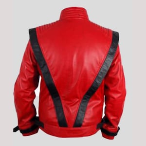 May include: A bright red jacket featuring prominent black leather-like stripes that form a V-shape across the back and shoulders. The garment includes a high collar, ribbed detailing on the shoulders, and black adjustable straps at the waist and cuffs.