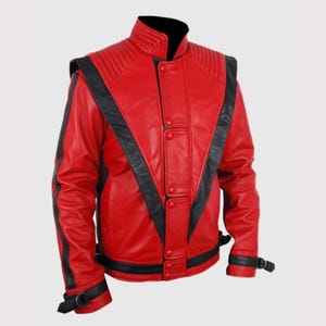 May include: A bright red leather jacket featuring bold black V-shaped panels across the chest and back. The jacket includes a high stand-up collar, ribbed shoulder detailing, a central button-down placket, and black buckled straps at the cuffs.