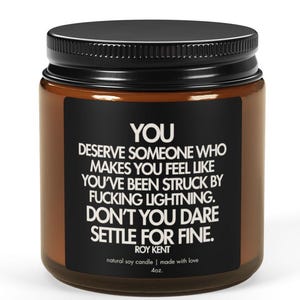 May include: A brown glass jar with a black lid. The jar has a label with white text that reads: "YOU DESERVE SOMEONE WHO MAKES YOU FEEL LIKE YOU'VE BEEN STRUCK BY FUCKING LIGHTNING. DON'T YOU DARE SETTLE FOR FINE."