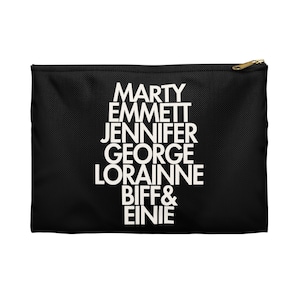 May include: Black zippered pouch with white text listing names: Marty, Emmett, Jennifer, George, Lorainne, Biff & Einie. The pouch has a gold-colored zipper and pull.