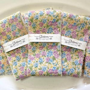 May include: Three pieces of floral fabric ribbon with a frayed edge. Each ribbon has a label that reads "Prairie Blossom Vintage, Serve Restore Believe".
