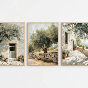 Pode incluir: Um conjunto de três impressões de arte de parede emolduradas retratando cenas mediterrâneas. As imagens apresentam edifícios de pedra, oliveiras, vasos de terracota e caminhos pavimentados em tons suaves de verde, bege e castanho.
