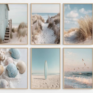 May include: A set of six framed wall art prints featuring coastal scenes. The images display a light blue beach cabin, a sandy path through dunes, tall beach grass, various seashells on white sand, a surfboard on a beach, and birds over ocean waves.