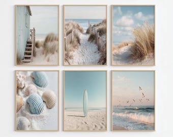 May include: A set of six framed wall art prints featuring coastal scenes. The images display a light blue beach cabin, a sandy path through dunes, tall beach grass, various seashells on white sand, a surfboard on a beach, and birds over ocean waves.