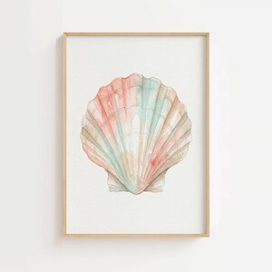 May include: A framed watercolor print featuring a single scallop shell centered on a white background. The shell displays soft, blended washes of pastel pink, peach, and mint green, with defined vertical ridges and a light wooden frame.