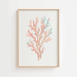 May include: A framed wall art print featuring a watercolor illustration of a branching coral structure. The coral is rendered in soft shades of peach, coral pink, and pale seafoam green, set against a plain white background within a light wood frame.