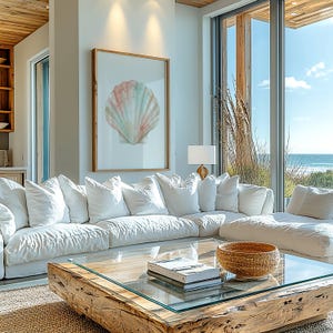 May include: A large white sectional sofa with multiple cushions sits in front of a low coffee table featuring a thick, natural wood base and a glass top. On the table rests a stack of books and a round, woven basket bowl.