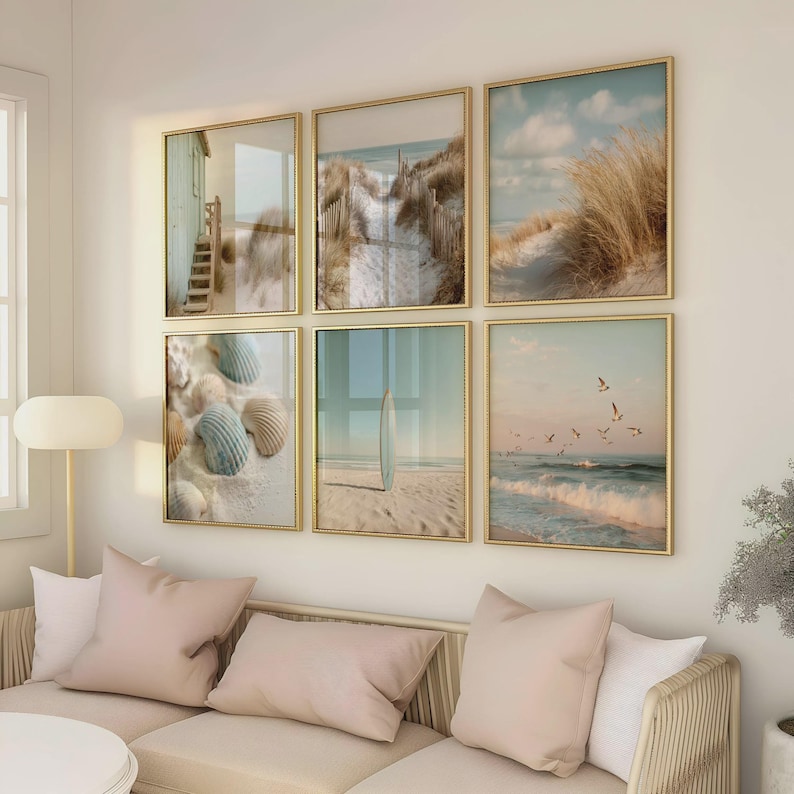 May include: A gallery wall set of six square framed prints featuring coastal scenes, including a beach house, sand dunes with tall grass, seashells on sand, a surfboard standing on a beach, and seagulls flying over ocean waves at sunset.