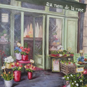 May include: An oil painting of a flower shop with the text "au nom de la rose" above the entrance. The shop displays various potted flowers in red, white, and blue hues, with price tags. The storefront is painted in shades of green.