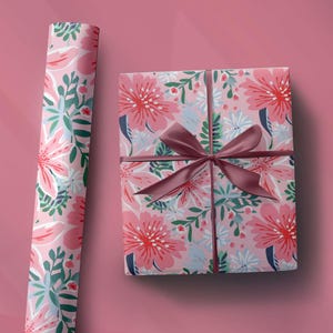 May include: Pink floral gift wrap with a matching wrapped gift box and a roll of paper. The design features large pink flowers, green leaves, and blue accents. A dark pink ribbon is tied around the box.