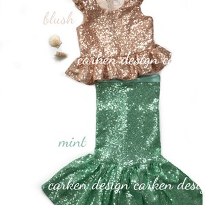 Puede incluir: Un disfraz de sirena de lentejuelas de dos piezas para ni&ntilde;as. La parte superior es de color rosa melocot&oacute;n con un dobladillo con volantes y la falda es de color verde menta con una cola de sirena.