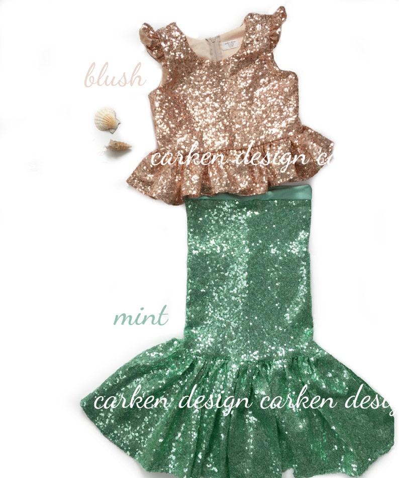 Puede incluir: Un disfraz de sirena de lentejuelas de dos piezas para ni&ntilde;as. La parte superior es de color rosa melocot&oacute;n con un dobladillo con volantes y la falda es de color verde menta con una cola de sirena.