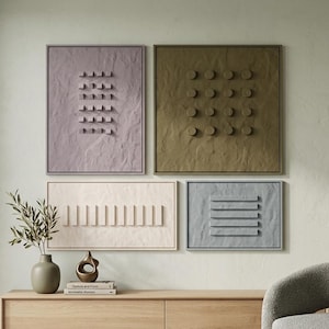 May include: Four framed wall art pieces with textured surfaces and geometric designs. The art pieces are in shades of lavender, olive green, cream, and gray. A wooden console table with a vase and decorative objects sits below the art.