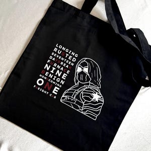 Könnte beinhalten: Schwarze Tragetasche mit einer weißen Grafik eines Gesichts und eines Torsos einer Figur. Der Text auf der Tasche enthält die Wörter "Longing, Rusted, Seventeen, Daybreak, Furnace, Nine, Benign, Homecoming, One, Freight Car."