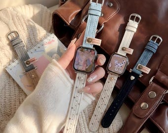 May include: Several smart watch bands in various colors and styles. The bands include light blue denim, white with small silver dots, and a dark navy blue band. Each band has a silver buckle and a small heart-shaped charm.