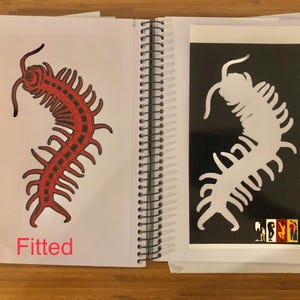 May include: A spiral-bound notebook open to two pages. One page features a red centipede illustration with the word "Fitted" below. The facing page has a white centipede silhouette on a black background.