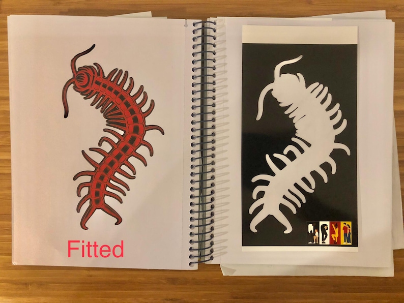 May include: A spiral-bound notebook open to two pages. One page features a red centipede illustration with the word "Fitted" below. The facing page has a white centipede silhouette on a black background.