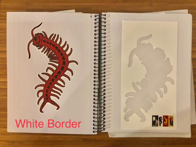 May include: Open sketchbook with a red and black centipede illustration on the left page and a centipede stencil on the right. The text "White Border" is visible at the bottom left of the left page. The sketchbook is open on a wooden surface.