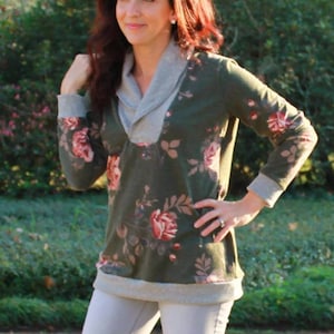 May include: A green floral print long-sleeve shirt with a gray cowl neck. The shirt has a relaxed fit and a casual style.