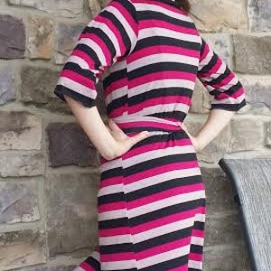 May include: A pink and black striped midi dress with a wrap style and a tie belt. The dress is made of a soft, stretchy fabric.